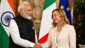 Italian Prime Minister Giorgia Meloni and Indian Prime Minister Narendra Modi smiling and shaking hands at a joint press conference in Rome.